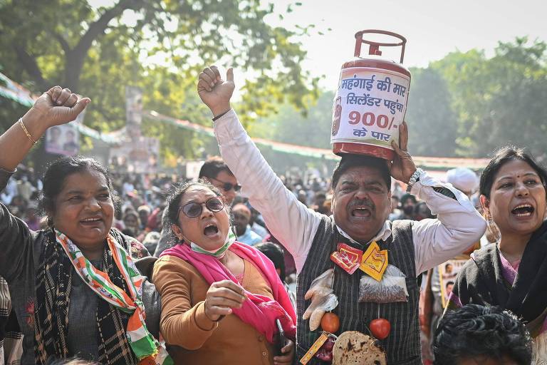 Manifestante carrega sobre a cabeça simulacro de botijão de gás de cozinha em protesto contra o avanço da inflação em Nova Deli, na Índia 