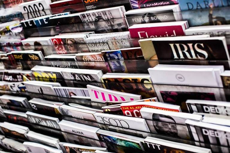 Foto mostra prateleiras de uma banca cheias de revistas.
