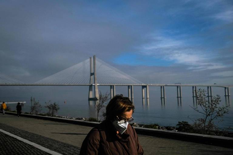 Mulher com máscara caminha no parque Tejo, em Lisboa, perto da ponte Vasco da Gama