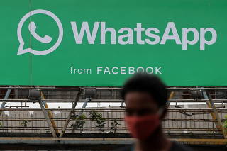 A man walks past a hoarding of the WhatsApp application installed at a skywalk in Mumbai, India