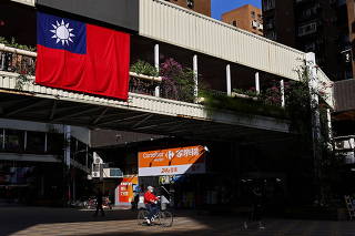 FILE PHOTO: A man cycles past a Taiwan flag in Taipei