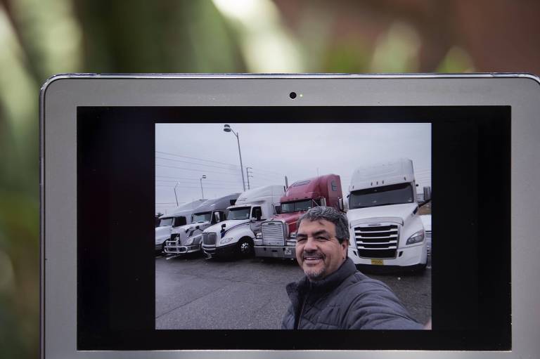 Roni aparece numa videochamada, na tela de um computador, sorrindo em frente a caminhões