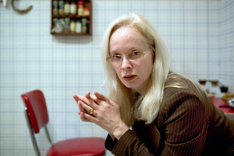 mulher branca de cabelos grisalhos e longos e óculos em cozinha 