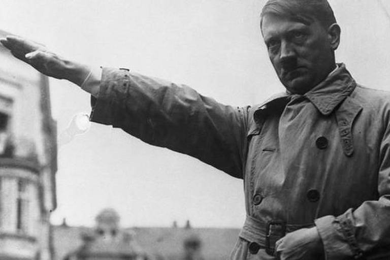 Imagem em primeiro plano mostra Hitler sério com um dos braços estendidos para frente