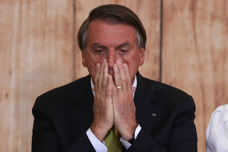 O presidente Jair Bolsonaro (PL) com as duas mãos sobre o rosto, ao lado do nariz, tapando a boca