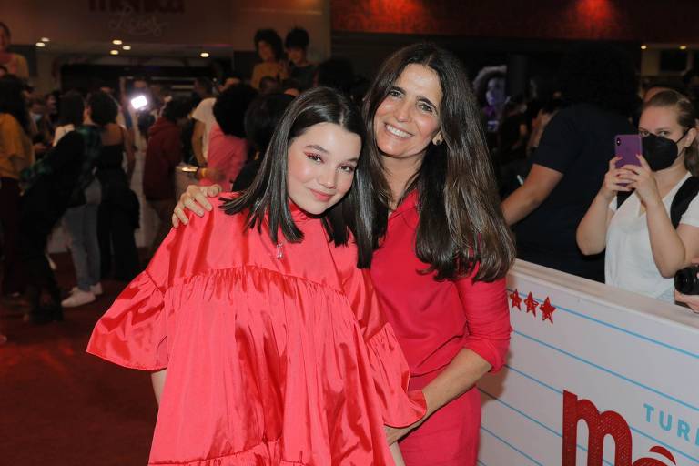 A atriz adolescente Giulia Benite, de vestido rosa, está abraçada com a atriz Malu Mader, de blusa vermelha