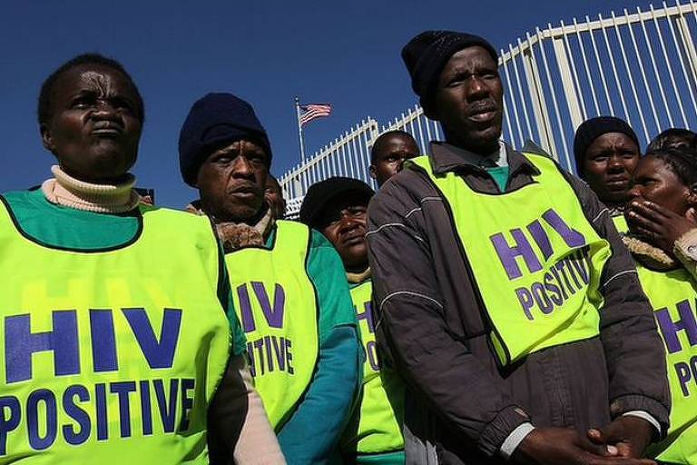 Imagem de protesto mostra pessoas negras usando um colete escrito: HIV positive