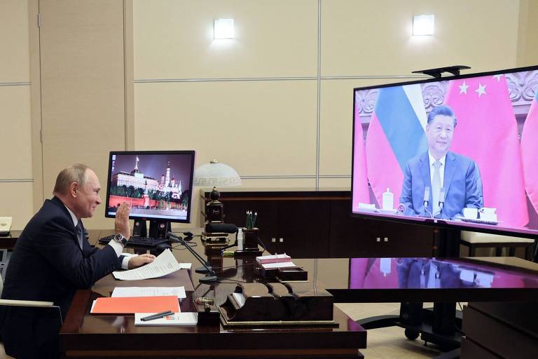 Em sua residência perto de Moscou, Putin acena a Xi durante videoconferência
