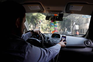 FILE PHOTO: Uber driver checks the route on a mobile phone inside his car in Mexico City