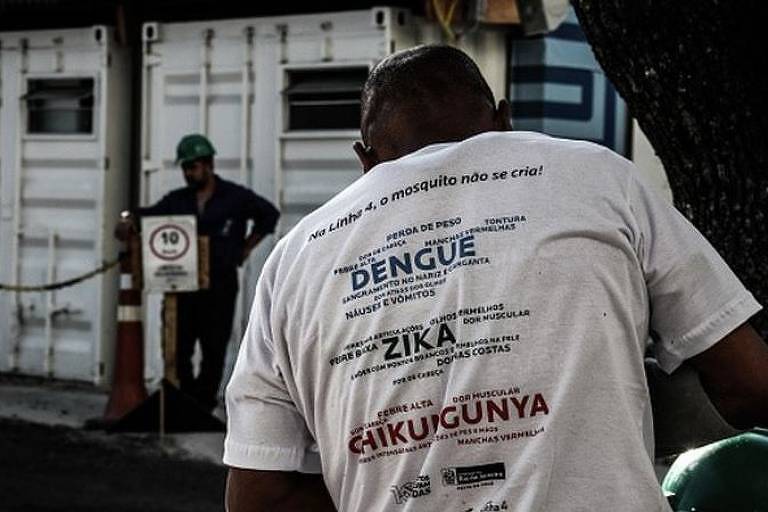 Em destaque, homem de costas usa camiseta branca escrito: dengue, zika e chikungunya