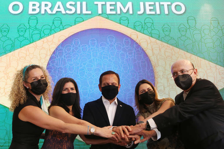 Imagem do governador com os quatro integrantes da equipe dando as mãos em frente a uma imagem da bandeira do Brasil com a frase O Brasil tem jeito