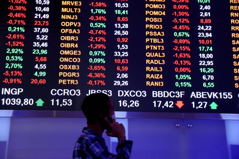 Homem passa diante do quadro eletrônico que mostra flutuação dos índices de mercado na sede da B3, a Bolsa de Valores brasileira, em São Paulo (SP)