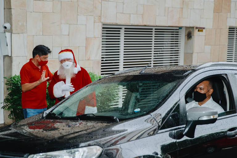 Dois homens conversam, um deles vestido de Papai Noel