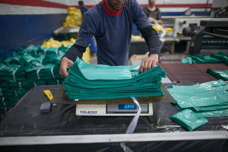 Funcionário de fábrica de embalagens pesa sacolas plásticas