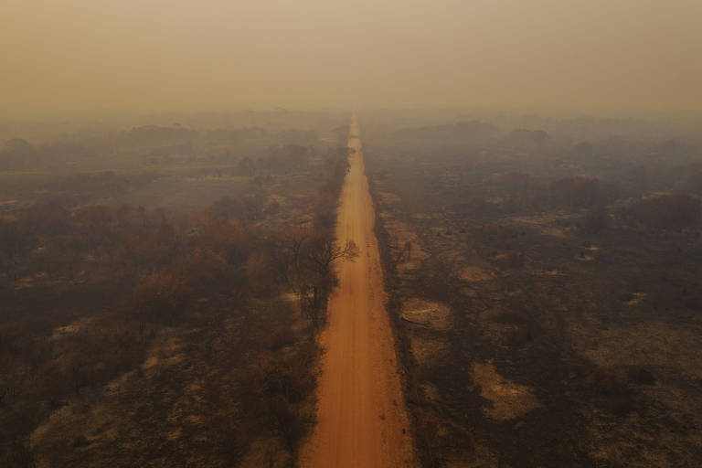 Estrada vista de cima, coberta de fumaça alaranjada