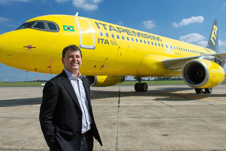 homem branco de terno preto em frente a um avião amarelo