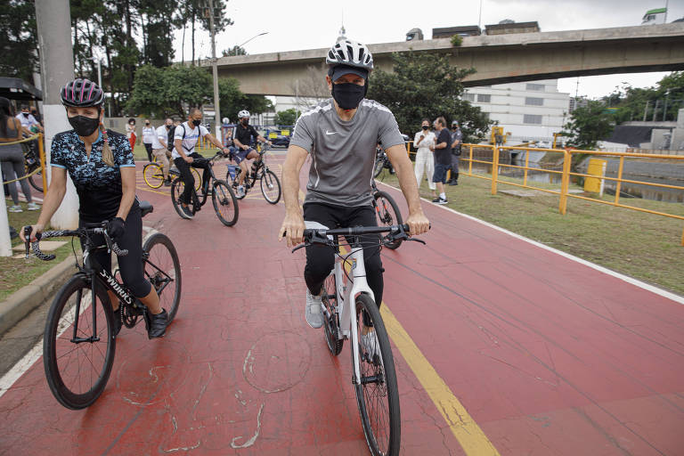 Doria pedala bicicleta ao lado de outros ciclistas