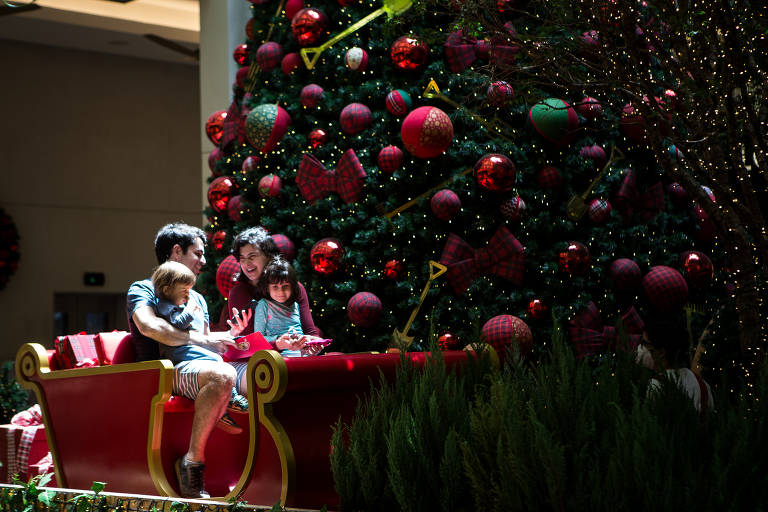 Família ao lado de árvore de Natal, para compras no final de semana pré-natal em shopping