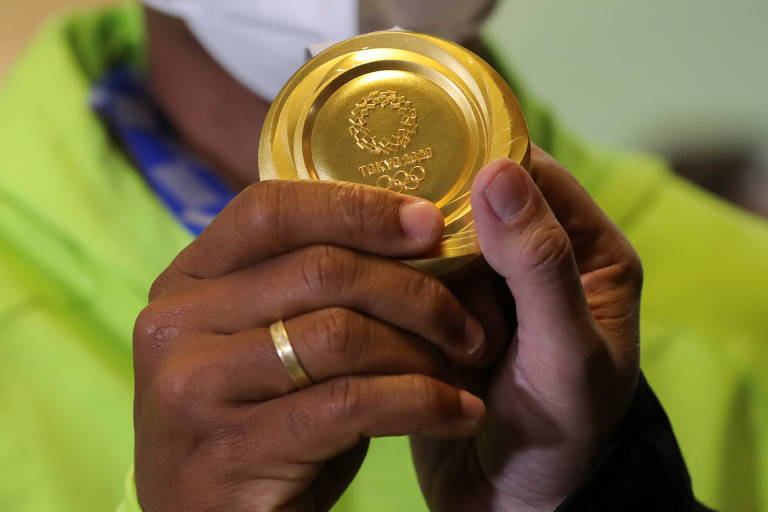 Mãos de Isaquias segurando a medalha dourada