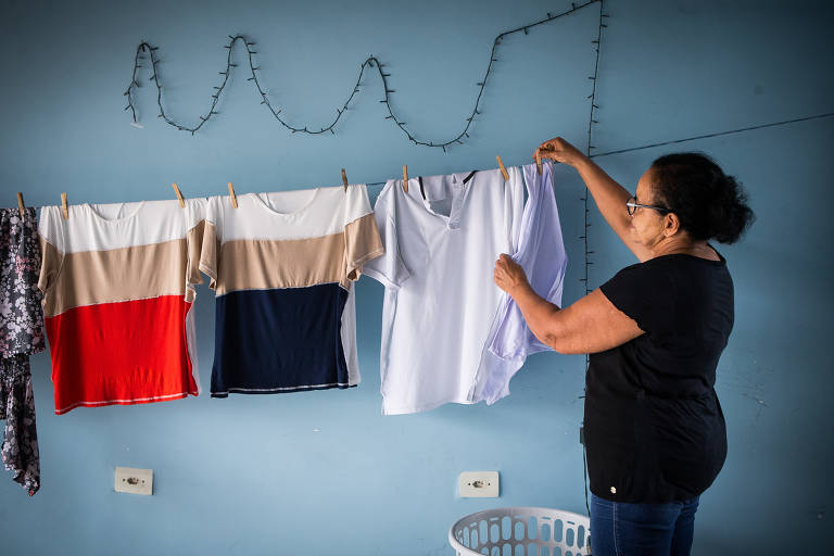 Pensionista de blusa preta, óculos e cabelo preso pendura roupas no varal da garagem de sua casa, em Indaiatuba; Neuza teve diagnóstico positivo para HPV com teste de DNA