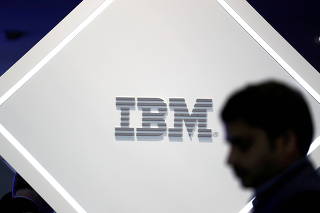 FILE PHOTO: A man stands near an IBM logo at the Mobile World Congress in Barcelona