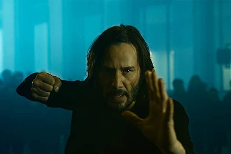 Cena de 'Matrix Resurrections', com ator de frente para câmera em cena de ação