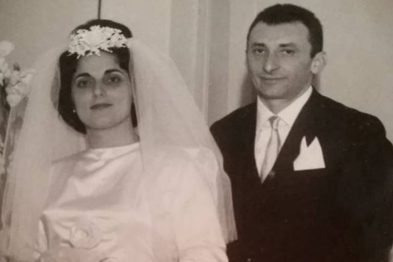 Imagem em preto e branco mostra mulher vestida de noiva ao lado de homem de roupa social