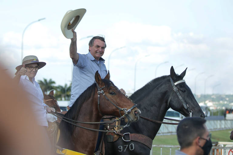 O presidente Jair Bolsonaro chega de cavalo e discursa num carro de som durante um protesto em defesa de seu governo, em maio de 2021