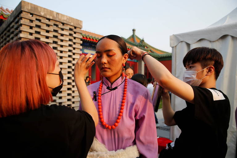 mulher chinesa é maquiada em intervalo de desfile