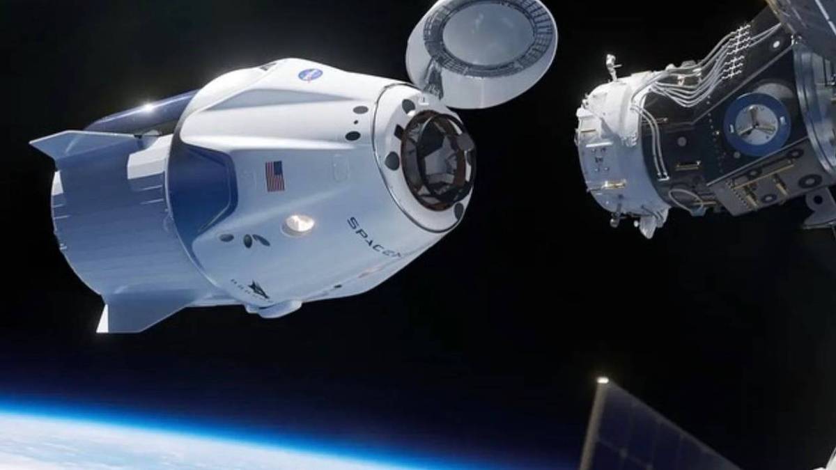 Cápsula espacial branca chega perto de estrutura de metal, no espaço