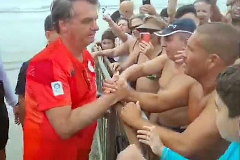 O presidente Jair Bolsonaro cumprimenta apoiadores aglomerados na Praia Grande, no litoral paulista