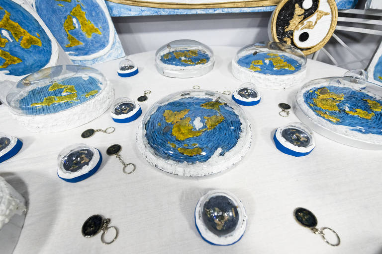 Objetos dispostos sobre uma mesa simulam a Terra com formato plano em conferência sobre terraplanismo realizada em São Paulo, no Teatro Liberdade