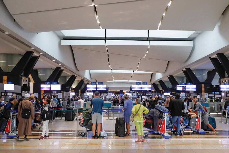 Viajantes tentam conseguir voos para sair da África do Sul, no aeroporto internacional de Joanesburgo, após detecção da variante ômicron