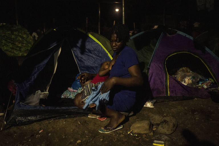 Migrante haitiana amamenta seu filho em um acampamento improvisado em Bajo Chiquito, no Panamá; milhares cruzam a floresta de Darién para tentar chegar aos EUA