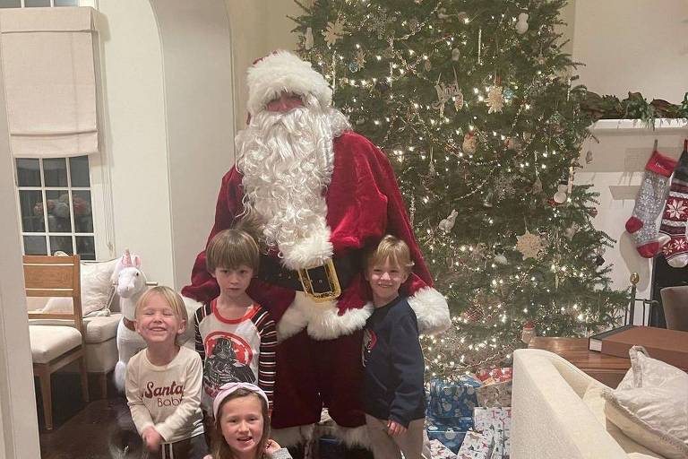 Homem vestido de Papai Noel com seis crianças