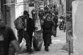 Policiais carregam corpo durante operação na favela do Jacarezinho