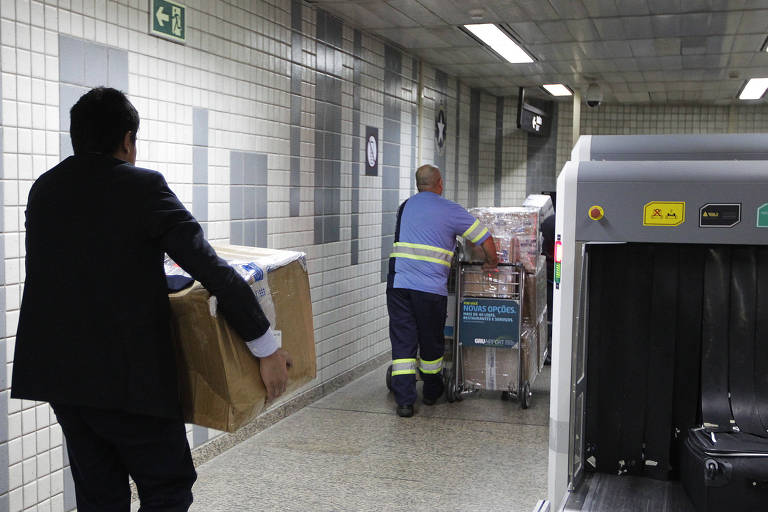 Funcionário da alfândega carrega pacote com produtos importados retidos no aeroporto de Guarulhos