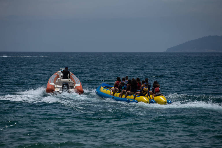 Lancha puxa banana boat cheia de pessoas em meio ao mar
