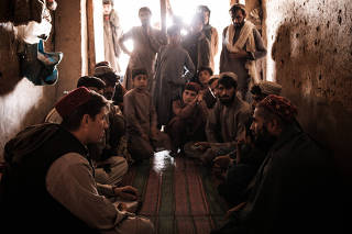 New York Times reporter Thomas Gibbons-Neff, left in red hat, interviews villagers in Marjah, Afghanistan, on Nov. 8, 2021.  (Jim Huylebroek/The New York Times)