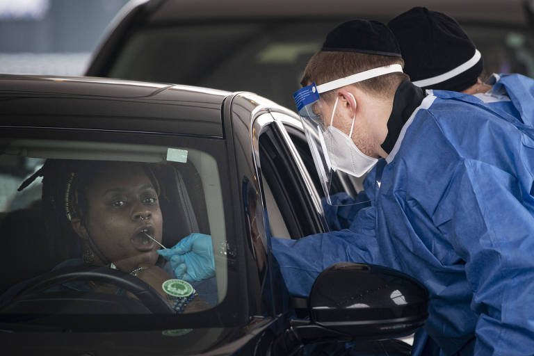 A health care worker administers a COVID-19 test at a walk-up and drive-thru site in Baltimore on Thursday, Dec. 30, 2021. In the United States, where the omicron variant of the coronavirus is spreading quickly, Maryland is among 16 states and Puerto Rico recording their all-time case records. (Al Drago/The New York Times)