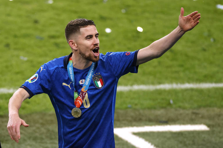 Com a medalha no peito e o braço esquerdo na direção da torcida, o ítalo-brasileiro Jorginho festeja no estádio de Wembley a conquista da Itália na Eurocopa de 2021