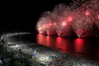 People gather to watch fireworks explode over Copacabana beach during New Year celebrations in Rio de Janeiro