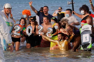 People wearing costumes participate in a traditional New Year's Day Swim in Calais