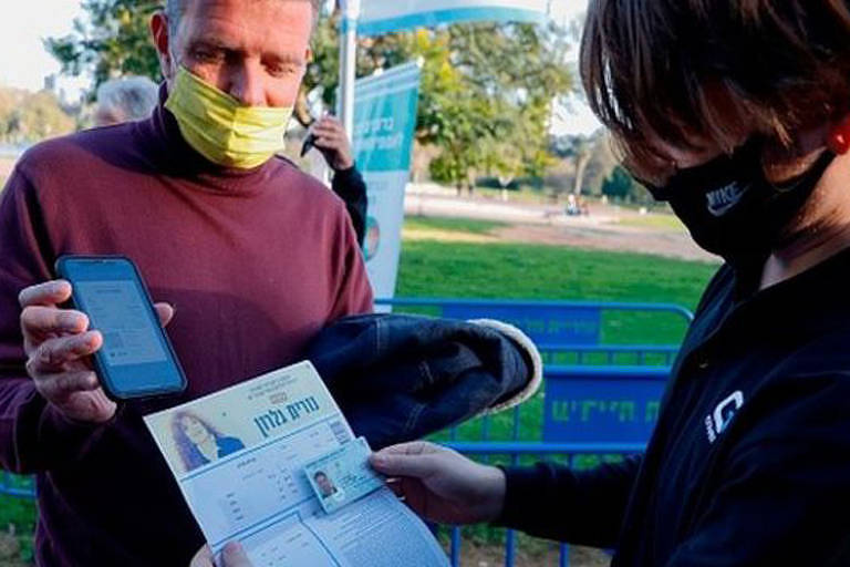 Homem mostra o passaporte da vacina para um funcionário antes de entrar em um evento fechado
