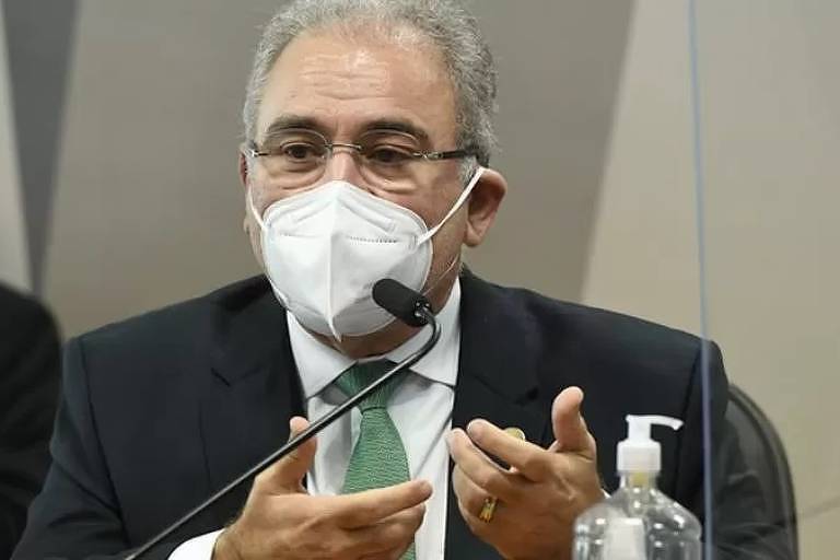Imagem em primeiro plano mostra Marcelo Queiroga de máscara de frente para um microfone