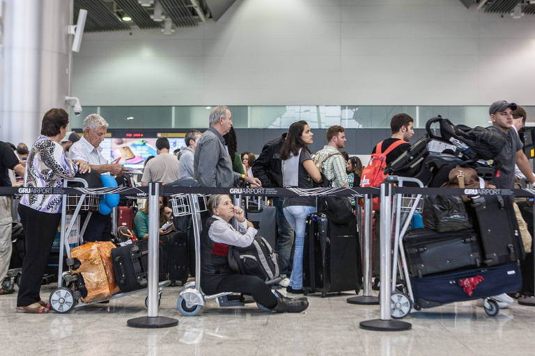 Pessoas de várias idades com malas, em fila de aeroporto 