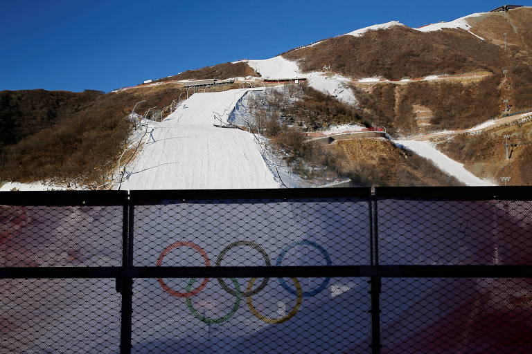 Os anéis olímpicos em grade à frente de uma montanha de neve