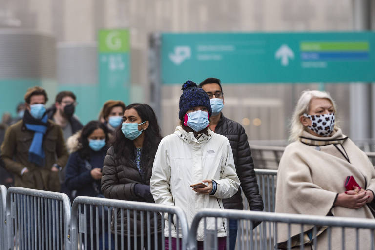 Pessoas em fila com máscara e roupas de frio
