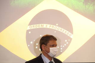 Brazil's Minister of Infrastructure Tarcisio Gomes de Freitas walks past a projection of the Brazilian flag during a press conference at Federation of Industries of the State of Sao Paulo (FIESP) in Sao Paulo