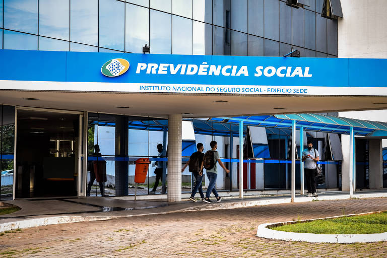 Pessoas passam em frente a prédio da Previdência Social INSS em Brasília